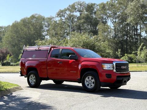 A red 2018 GMC Canyon pickup truck with a fitted bed cover parked on a road