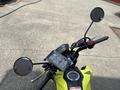 A 2018 Honda Grom motorcycle showcasing its handlebars with mirrors a digital display and controls in a vibrant yellow color