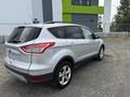 A silver 2015 Ford Escape parked at an angle showing its rear and side profile with a compact SUV design and alloy wheels