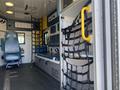 Interior of a 2011 Chevrolet Express with blue seating a yellow handle and black harness netting along the walls