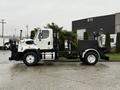 A 2016 Freightliner 108SD truck with a white cabin and black chassis is positioned sideways showcasing its sturdy build and open bed for various uses