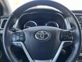Steering wheel of a 2018 Toyota Highlander with controls for audio and cruise settings and the Toyota logo in the center