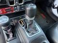 Close-up of the gear shift of a 2021 Jeep Wrangler showing the gear selector with P R N D M options and a textured black shift knob with a silver trim