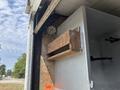 A wooden shelf mounted on a metallic box inside a vehicle with a light fixture above it