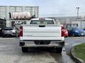 A 2024 Chevrolet Silverado 1500 viewed from the rear showcasing its white paint and pronounced Silverado branding on the tailgate