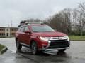 A red 2016 Mitsubishi Outlander parked on a wet road with a sleek design featuring a chrome front grille and modern headlights