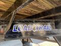 A close-up view of a Load Trail logo on a black metal gooseneck trailer with wooden flooring