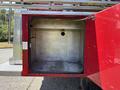 An open storage compartment of a red 1994 Volvo FE 42 showing a metallic interior with a circular hole in the back wall