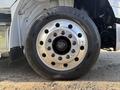 A close-up of a 2022 Freightliner M2 106 wheel featuring a shiny chrome rim with multiple holes and a large tire labeled 29560R22.5