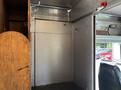 Interior view of a 2011 Workhorse W62 featuring metallic walls and a wooden panel along one side with several hooks attached