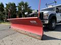 A red snow plow attached to a 2008 Ford F-450 SD truck with a black grille and two front lights