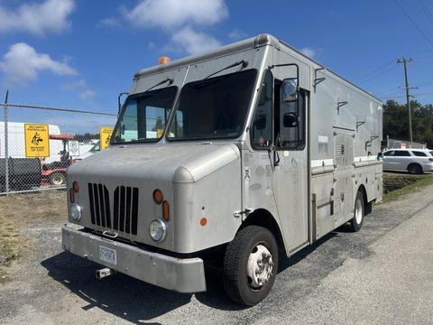 A 2009 Workhorse W62 delivery truck with a silver exterior and a boxy design featuring large front windows and multiple compartments on the side