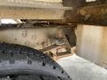 Underneath a 2015 Ford F-550 showcasing the suspension system with a large tire visible in the foreground and various metal components and supports in view