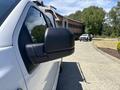 A side view mirror of a white 2019 Ford F-150 with a black casing