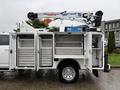 A white 2024 RAM 5500 truck with an extended boom lift mounted on top and storage compartments opened on the side revealing metal drawers and tools inside