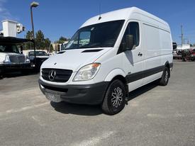 A white 2010 Mercedes-Benz Sprinter van with a high roof and black accents positioned at an angle with alloy wheels