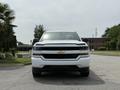 A white 2018 Chevrolet Silverado 1500 is parked facing forward with a distinctive black grille and Chevy bowtie emblem in the center