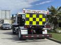 A 2016 Freightliner 108SD with a bright yellow and black checkerboard pattern on its rear panel parked in a lot