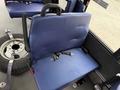 A blue fabric seat with a smooth surface featuring two seatbelt slots and a handgrip, positioned in a vehicle interior