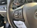 Steering wheel controls of a 2013 BMW X3 featuring buttons for setting speed and managing cruise control