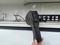 A close-up of a black rubber grip tool with two buttons held in a hand, likely used for a feature in a 2016 RAM 1500 truck