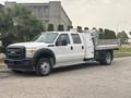 A 2014 Ford F-550 truck with a crew cab and a flatbed attachment featuring a metal tool box on the side