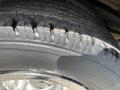 Close-up of a worn tire from a 2004 Ford Econoline showing deep treads and visible signs of age and use