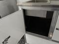 An open white storage compartment in a 2020 Freightliner MT45 with a metal interior and a sink on top