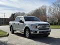 A 2018 Ford F-150 pickup truck in white with chrome accents and a spacious cab parked on a paved area
