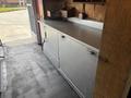 A silver metal countertop with cabinets below and various tools and storage items arranged on top inside a vehicle.