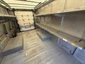A 2012 Ford Econoline van with metal shelving units along the walls and an open cargo area