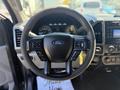 Steering wheel of a 2018 Ford F-150 with controls for audio and cruise settings prominently displayed