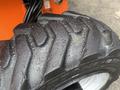 Close-up of a large tire from a 2012 JLG 660SJ with deep treads and visible droplets of water on its surface
