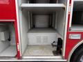 A 2007 Ford F-550 fire truck with empty storage compartments visible in the rear section