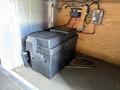 A black plastic storage box with a strap inside a compartment of a vehicle