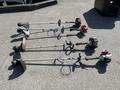 Four Shindaiwa gas powered weed eaters with various attachments lined up on a flat surface