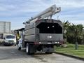 A 2012 International DuraStar 4300 bucket truck with a long extendable arm mounted on the top and a grey body designed for utility work