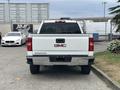 A white 2016 GMC Sierra 1500 truck viewed from the rear showing the GMC logo and Sierra lettering on the tailgate with a chrome bumper and blacked-out rear lights