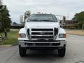 A 2013 Ford F-750 truck with a shiny chrome front grille and headlights facing forward showcasing its robust design and construction features