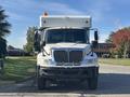 A white 2008 International 4400 truck with a flatbed and an amber light on top facing forward