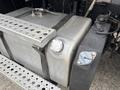 A silver fuel tank secured with straps next to a black reservoir on a 2013 Freightliner 114SD truck