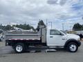 A 2011 Dodge Ram 5500 flatbed truck with a gray dump body parked on a street