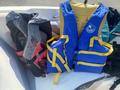 Two life jackets are displayed side by side with one being red and black and the other blue with yellow straps