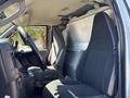 The interior of a 2019 GMC Savana with black cloth seats and a steering wheel visible while the passenger side has a spacious cargo area
