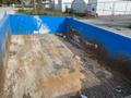 A blue dumpster with a rusty interior showing dirt and debris inside