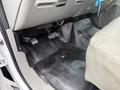 The interior floor of a 2006 Ford F-450 showing the driver's side with pedals and a gray seat visible
