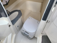 A compact marine toilet with a removable waste tank sits in a small restroom area of a 2013 Larson 238 boat featuring a sink and counter space