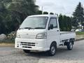 A white 2010 Daihatsu Hijet mini truck parked with a flatbed in the rear and a compact design featuring a simple front grille and headlights