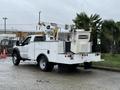 A white 2012 Ford F-450 SD with a utility truck bed and a lifting bucket on the back designed for maintenance work