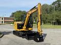 A 2022 Caterpillar 306 excavator with a yellow body and black tracks is positioned prominently with its arm raised and bucket attached ready for operation